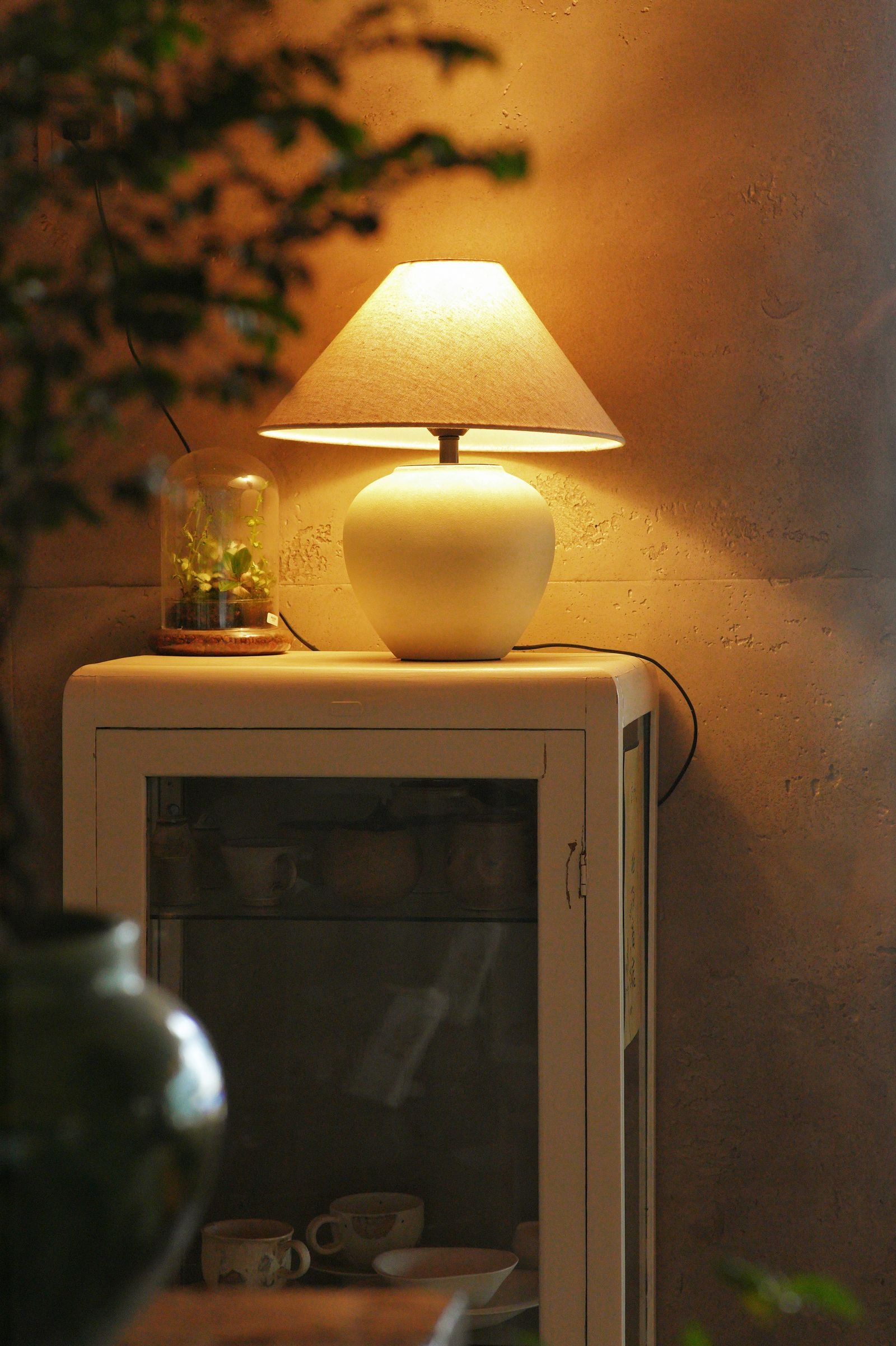 A warmly lit table lamp casting a soft pool of light in a dark room